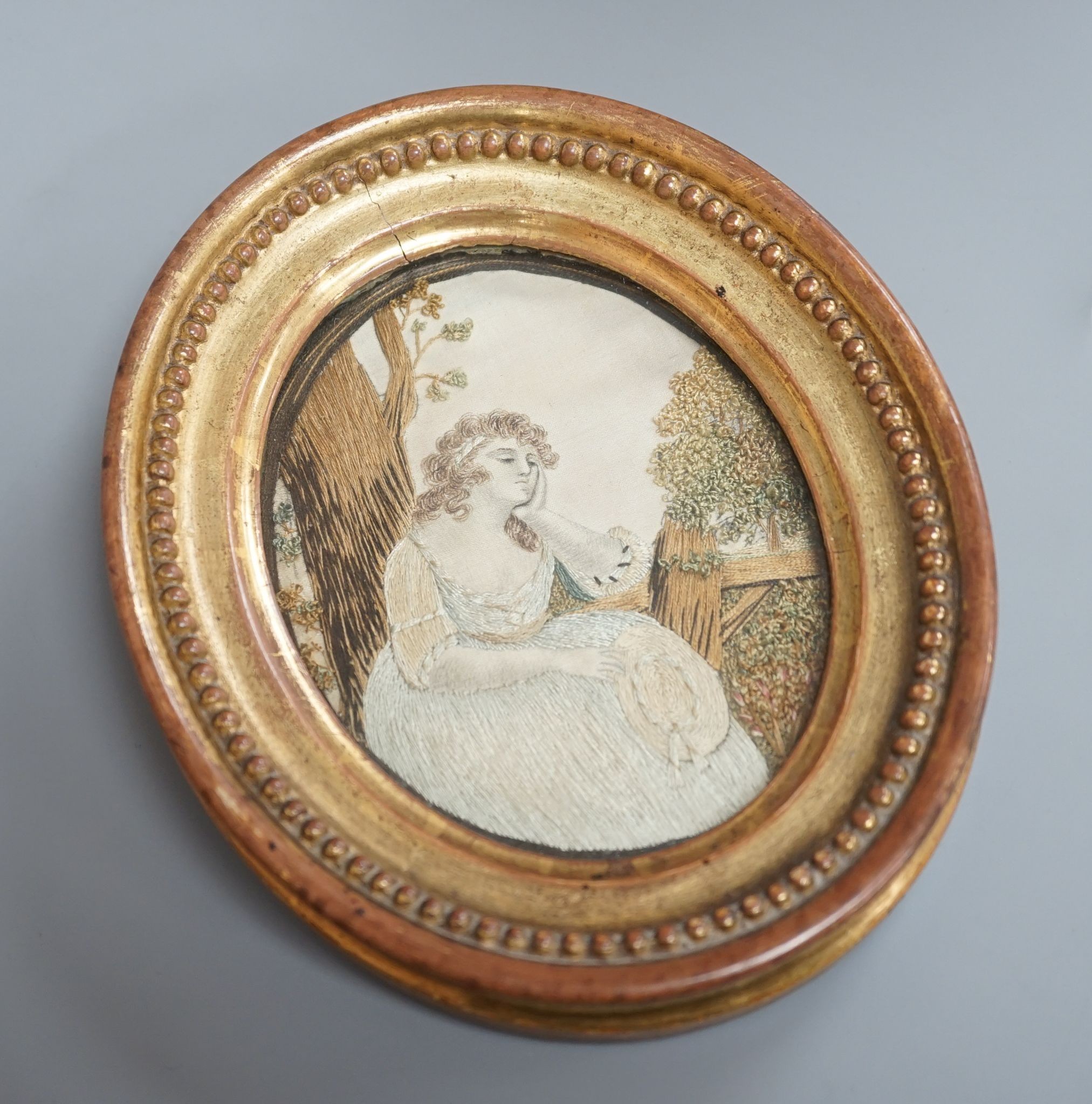 An oval gilt framed Regency silkwork of a seated girl 11x9cm
